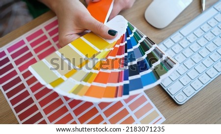 Top view of woman designer holding fan of colourful samples in hand. Designer searching proper colour for promotion. Design and art concept