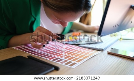 Close-up of woman searching proper colour for promotion and looking through magnifying glass. Graphic designer choosing colors samples Design concept
