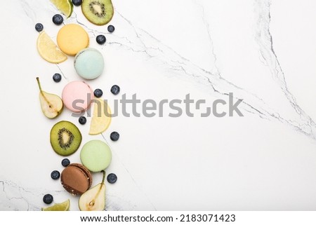 macaroons of different colors with different fruits on white marble. top view, space for text