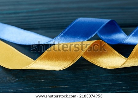 Ribbons in Ukrainian flag colors on wooden background