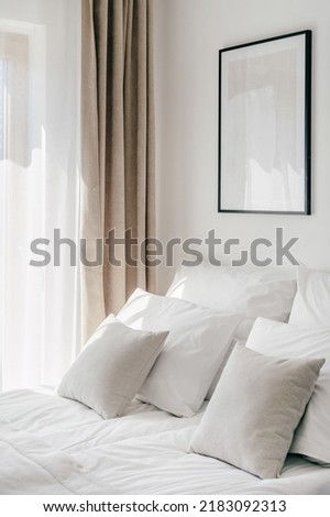 Side view of hypoallergenic pillows on bed and frame on wall, freshness idea, relax and spa, contemporary hotel room interior design details
