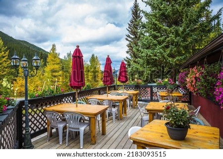 Cozy outdoor cafe. Holidays in autumn Canada. Wooden tables, plastic chairs and rolled up red awnings. 