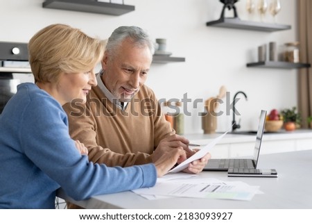 Smiling mature family check utility bills for water supply, gas and electricity, paying online together. Couple filling in quarterly and annual tax forms, calculation of pension savings Royalty-Free Stock Photo #2183093927
