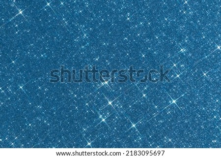 Sparkling texture. Abstract blue background with sparkles in the shape of stars. Festive backdrop for your projects.