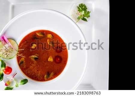 Soup with tomatoes, lime, mung bean salad, parsley, sesame seeds and rice in a plate on a black background