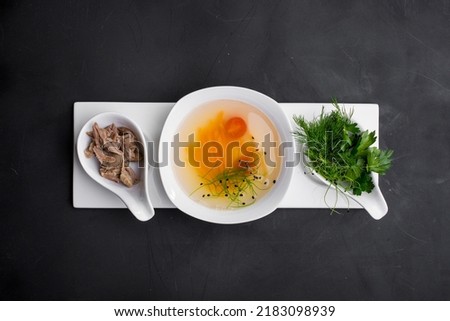 Soup with carrots, tomatoes, sesame seeds, meat, parsley and dill in a plate plate on a dark background