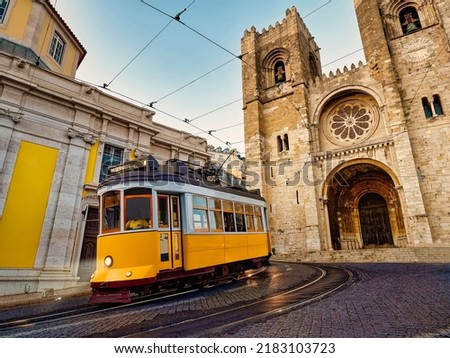 A famous yellow tram 28 passing in front of Santa Maria cathedral in Lisbon, Portugal at dusk or twilight Royalty-Free Stock Photo #2183103723