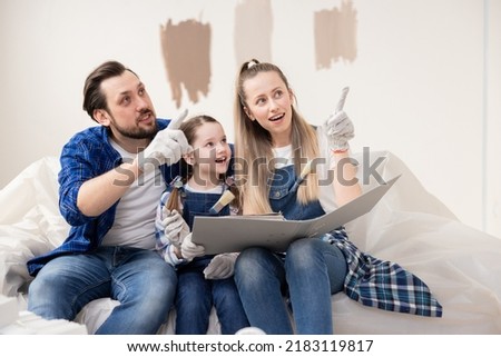 A husband and wife show their 8-year-old daughter a palette of colors that can be used to paint one of the walls in nursery. The child excitedly awaits new, renovated room.