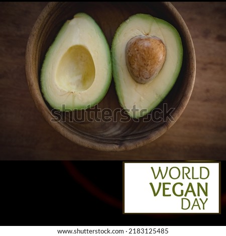 Composition of world vegan day text with avocado on wooden background. World vegan day and celebration concept digitally generated image.