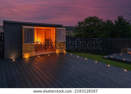 Ash grey composite decking built on two levels on a residential back garden with low voltage deck lights installed as well. Good Image for a landscape Gardiner Royalty-Free Stock Photo #2183128587