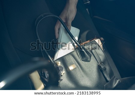 A hand that pulls out a wallet from the passenger seat of a car. Royalty-Free Stock Photo #2183138995