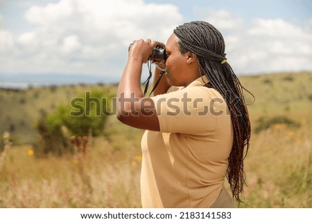 Side view of African American female guide looking for wildlife in Africa, copy space Royalty-Free Stock Photo #2183141583