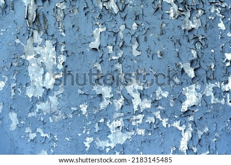 Gray stone cement abandoned wall with old peeling blue paint, many cracks, large flakes Royalty-Free Stock Photo #2183145485