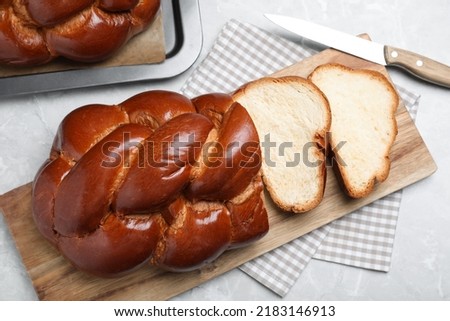 Cut homemade braided bread on grey table, flat lay. Traditional Shabbat challah