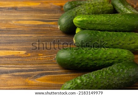 Fresh organic cucumbers on a brown wooden table. Salad ingredient. Fresh vegetables. Vegan food. Healthy food. Fresh organic vegetables.