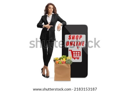 Businesswoman leaning on a smartphone and pointing at the screen with text shop online isolated on white background