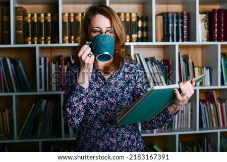 Woman at the library reading a book and drinking coffee. Business girl at the office 