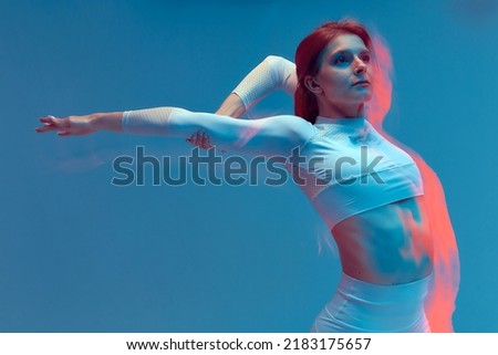 Sporty beautiful girl in white tracksuit on blue background. Isolated fitness model in studio with motion blur effect.