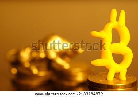 A bitcoin figurine on the background of a bull. Golden background.