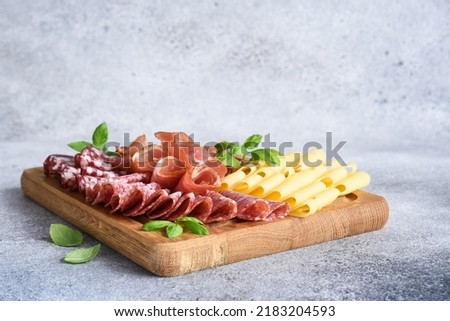 Cheese, prosciutto, salami on a wooden square board. Delicacy. Royalty-Free Stock Photo #2183204593