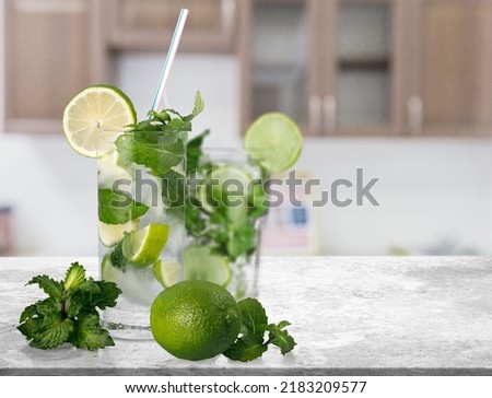 Organic cold refreshing lemonade drink or cocktail made of sparkling water, lime slices and fresh green mint leaves served in drinking glass with ice cubes