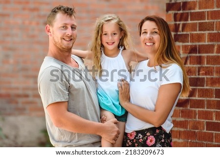 A Happy young family in a urban background. Father, mother and little daughter.