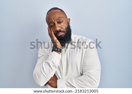 African american man standing over blue background thinking looking tired and bored with depression problems with crossed arms. 