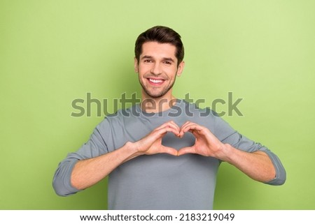Photo of nice millennial brunet guy show heart wear grey shirt isolated on green color background