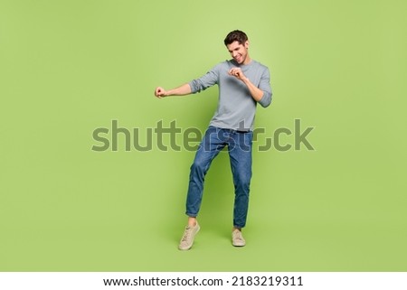 Full body photo of young good mood active energetic man dancing in club isolated on green color background