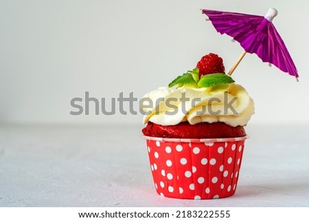 Cupcakes red velvet with pink cream decorated with raspberry and menthol stands under an umbrella. Copy space. Delicious delicacy. Muffin with cream. Cake. Royalty-Free Stock Photo #2183222555