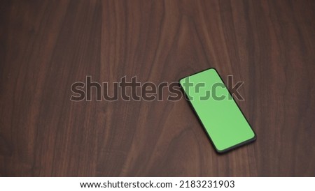 smarphone with green screen on walnut table