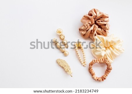 Collection of trendy silk elastic band scrunchies and pearl hair clips on white background. Diy accessories and hairstyles concept, luxury color Royalty-Free Stock Photo #2183234749