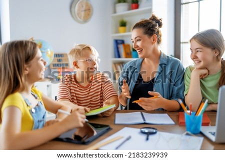 Happy kids and teacher at school. Woman and children are talking in the class. Royalty-Free Stock Photo #2183239939