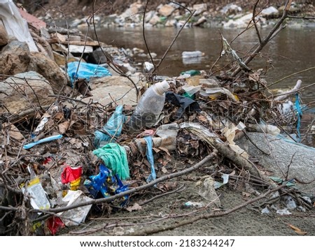 TIRANA, ALBANIA, MARCH 2022: Flooded plastic rubbish at the river bank as waste management issue. River debris and plastic garbage mix on a sandy river shore. The need to raise environmental awareness Royalty-Free Stock Photo #2183244247
