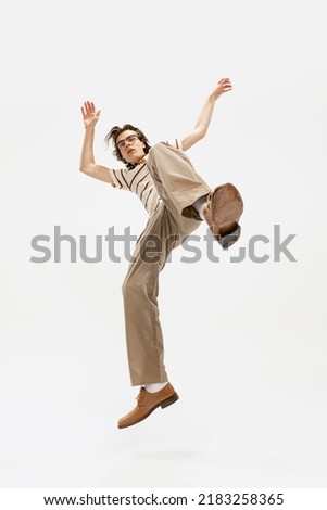 Portrait of expressive young man in vintage outfit dancing, posing isolated over white studio background. Retro party. Concept of retro fashion, style, youth culture, emotions, beauty, ad Royalty-Free Stock Photo #2183258365