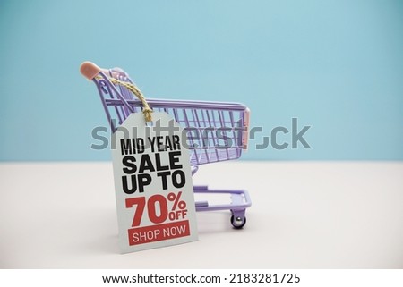 Mid Year Sale up to 70% off text message and shopping trolley cart on blue and pink background