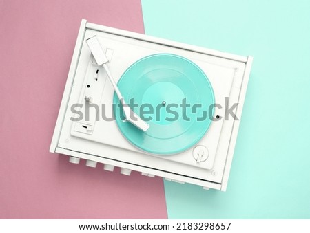 Turntable vinyl record player on pink blue background. Sound technology for DJ to mix and play music. White vinyl record. Minimalism. Flat lay. Top view
