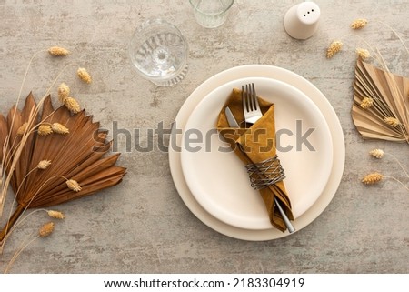 Table setting, plate with napkin and cutlery on a brown background, top view of the served table decorated with dry flowers Royalty-Free Stock Photo #2183304919