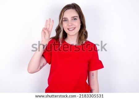 young caucasian woman wearing red T-shirt over white background showing and pointing up with fingers number three while smiling confident and happy.