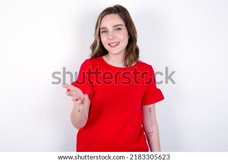 young caucasian woman wearing red T-shirt over white background smiling cheerful offering palm hand giving assistance and acceptance.