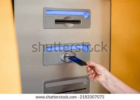Vertical photo. Woman's hand inserting the credit card in the ATM.