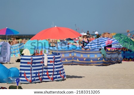 07.19.2022 niechorze, poland, Sun umbrella on a seaside beach in vacation together with a windscreen. Royalty-Free Stock Photo #2183313205