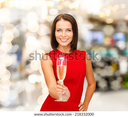 party, drinks, holidays, christmas and celebration concept - smiling woman in red dress with glass of sparkling wine over lights background