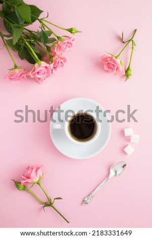 Coffee in the white cup and pink roses on the pink  background. Top view. Location vertical.