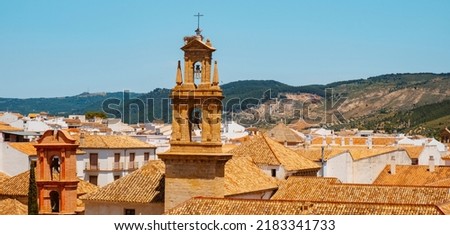 a view of the rooftops of the old town of Antequera, in the province of Malaga, Spain, highlighting the belfry of the San Zoilo Church in a sunny spring day, in a panoramic format to use as web banner