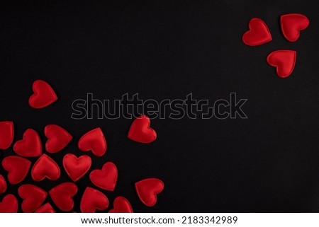Red hearts scattered on a black background for Valentine's day
