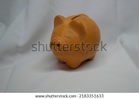 a clay piggy bank and some coins of different denominations