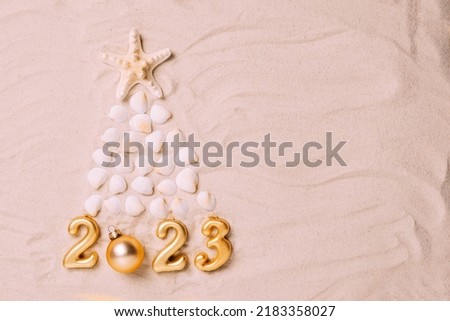 Creative Christmas tree made of shells and symbolic numbers of new year 2023 background of sea sand