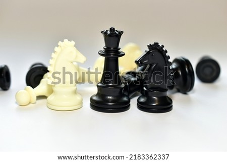 In the picture, there are chess pieces king and two white and black knights on a white table.