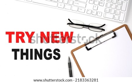 TRY NEW THINGS text written on white background with keyboard, paper sheet and pen Royalty-Free Stock Photo #2183363281